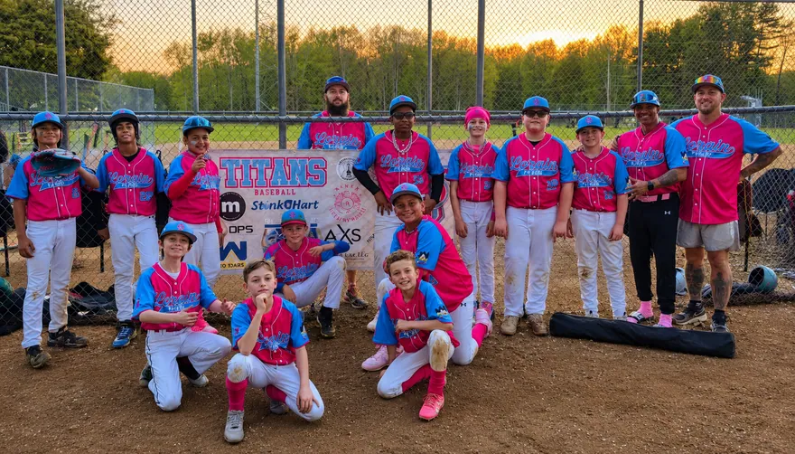 Youth baseball team in pink and blue sublimated jerseys, caps, socks and belts beside their team banner